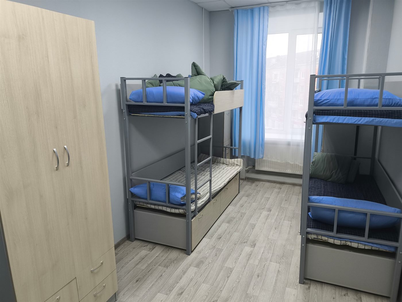 Комната в хостеле: шкаф и двухъярусные кровати у окна